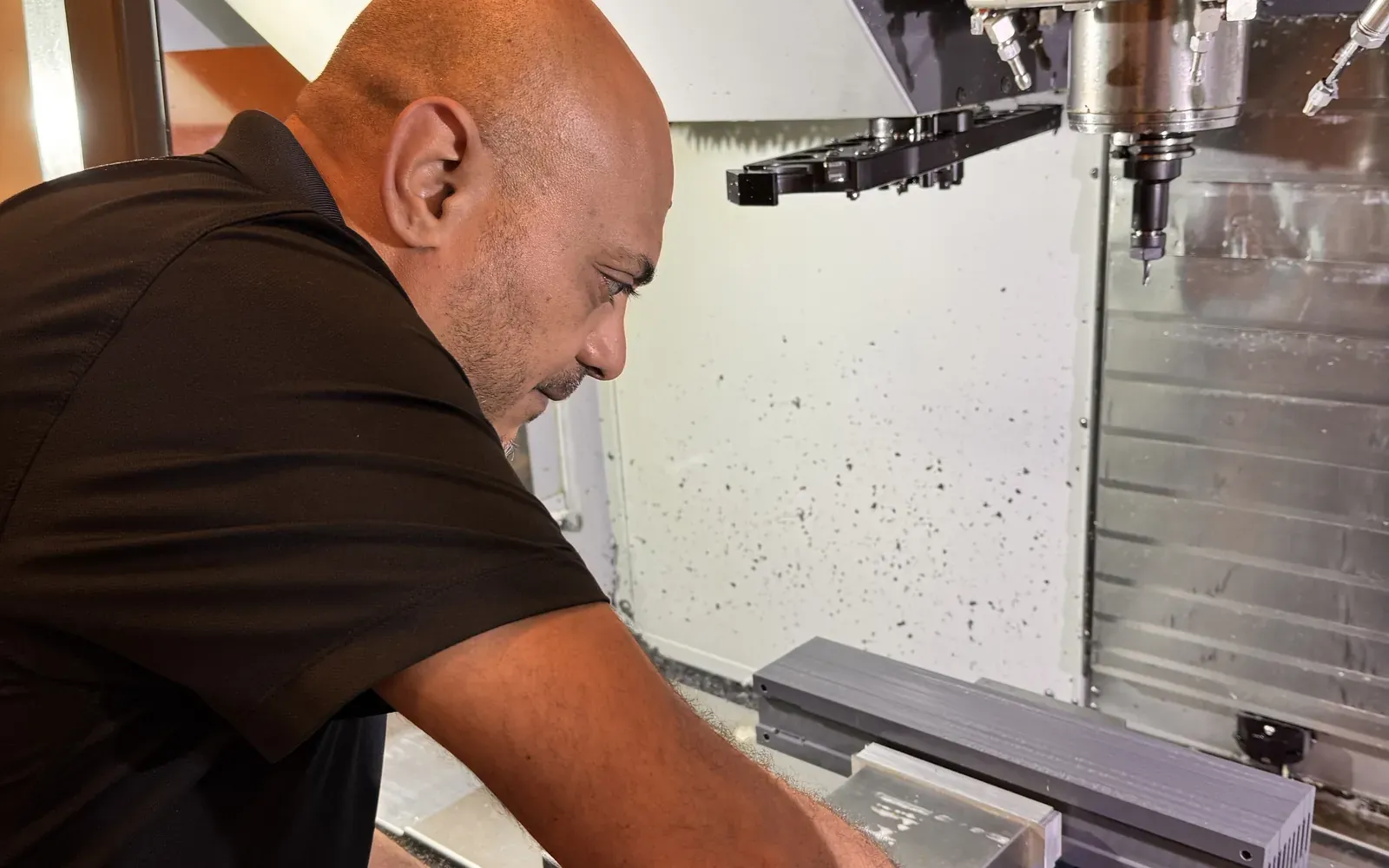 Michael Nessim loading a part into the vise of a Haas CNC mill by hand